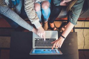 Three women discussing abot internmet marketing while pointing on a laptop.