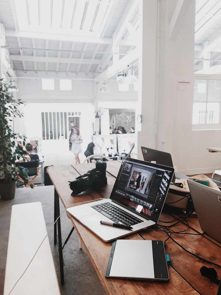 Laptops, tablet, and camera in the foregrgraphic in a white design studio.