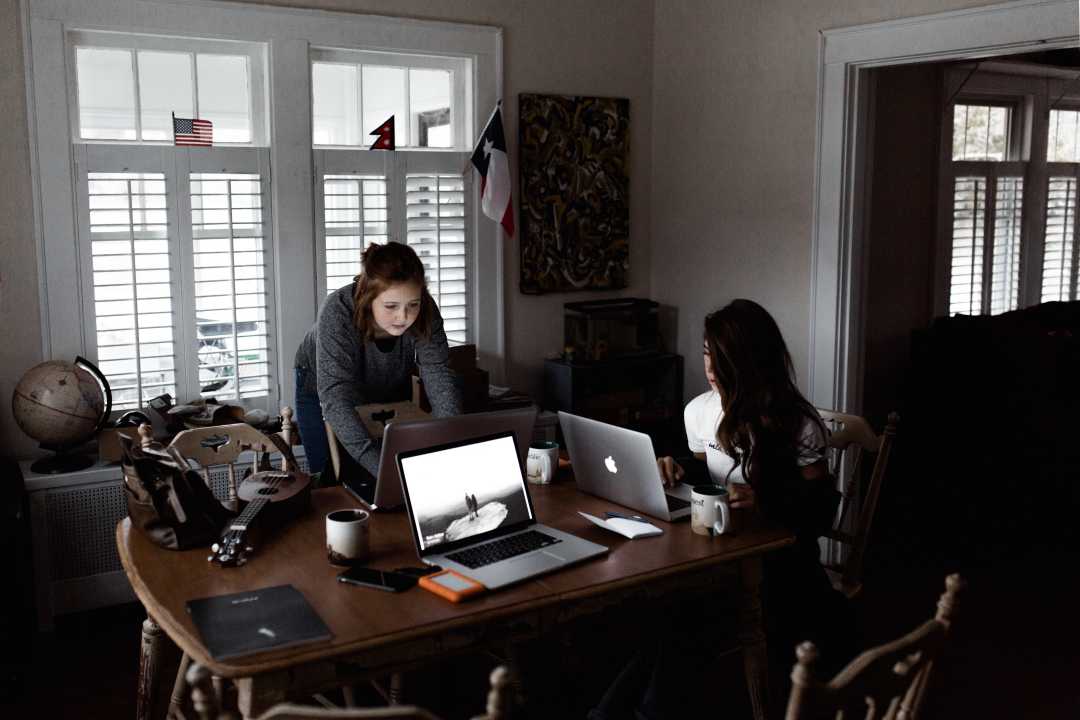 Two female web developers working in a brown table. Two female web developers working in a brown table.